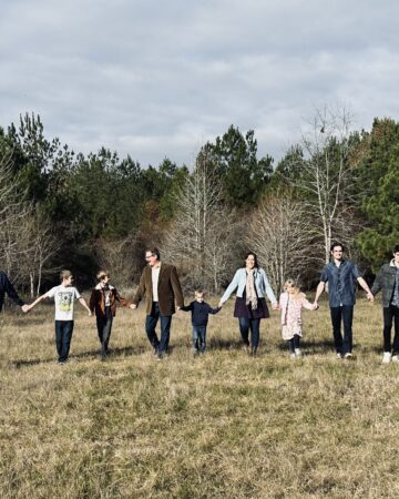 Family holding hands in field